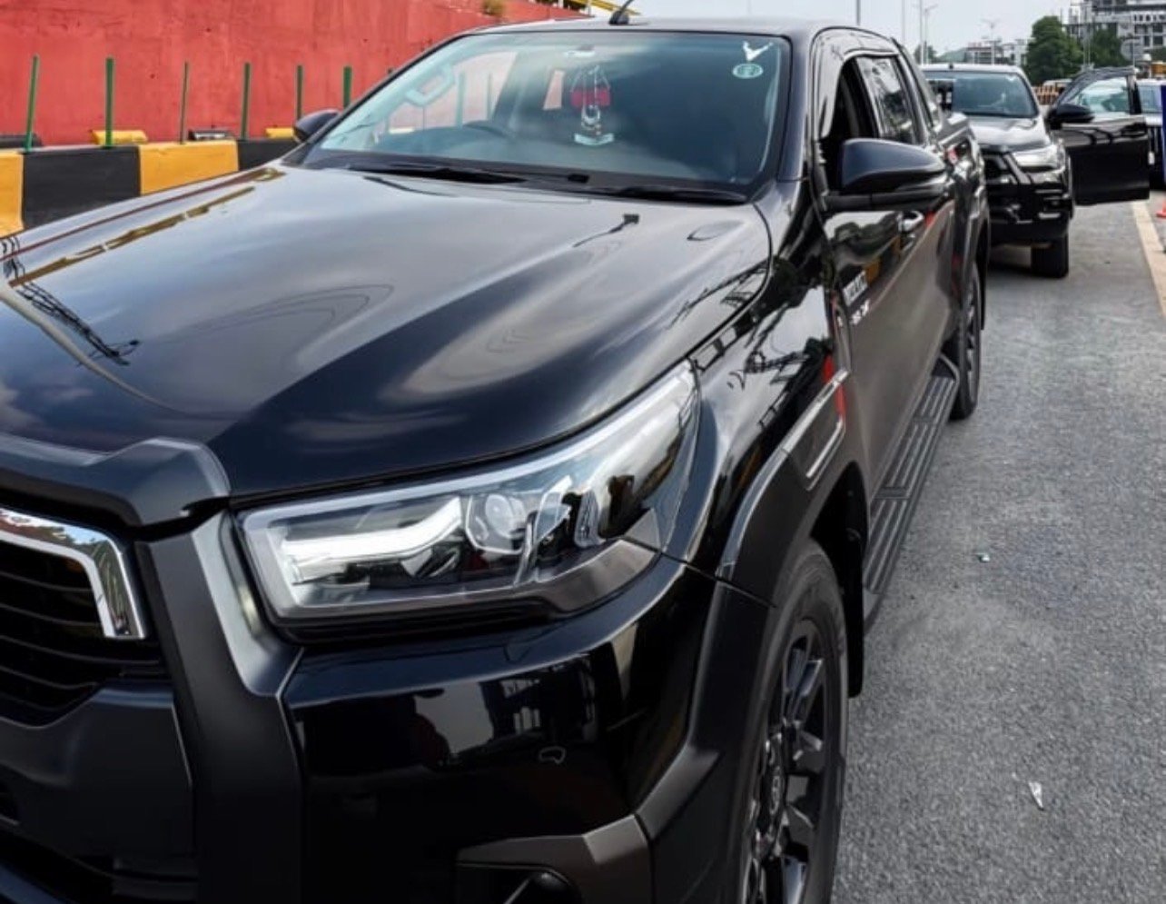 Professional uniformed driver holding open the passenger door of an executive sedan in Karachi